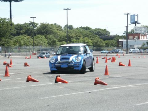 2001 Mercury Grand Marquis - Blue Mini Cooper S autocrossing on a sunny day with cones marking the course.
