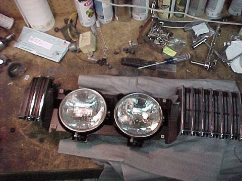 1967 Mercury Cougar - A car grille and two headlights are laid out on a workbench, surrounded by various tools and hardware.