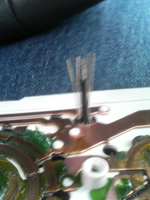 2000 Dodge Durango - Close-up view of a circuit board copper conductive paths and green epoxy encapsulation, with a central component holding thin metal pins.