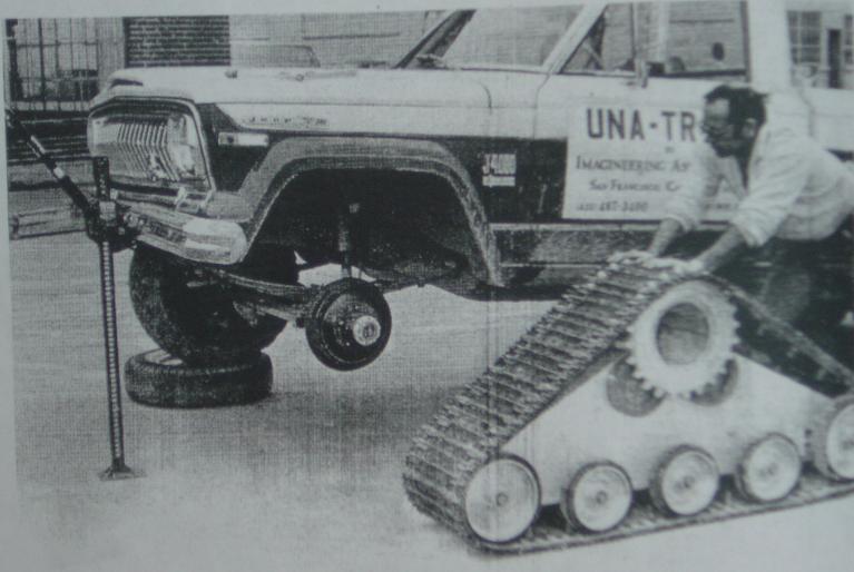 Jeep Wagoneer lifted by a jack, with a man working on a tracked vehicle next to it