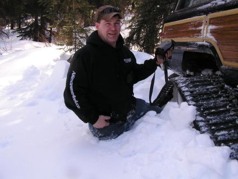2000 Ford E350 - A man is partially submerged in snow next to a vehicle equipped with tracks.