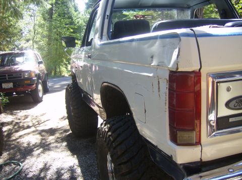 1986 Ford Bronco - A lifted white Ford Bronco is parked on a gravel road next to a red Toyota SUV.