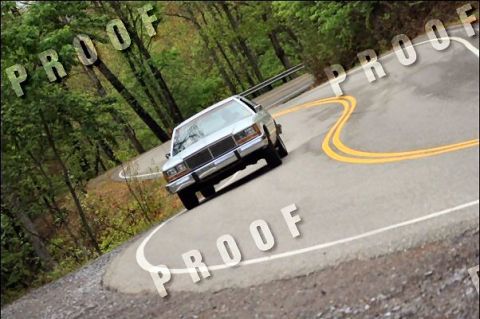 1985 Ford LTD Crown Victoria - A 1985 Ford Crown Victoria LTD navigates a sharp curve on a scenic mountain road.