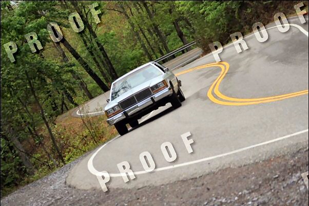 Silver 1985 Ford Crown Victoria LTD on a winding road with yellow double lines