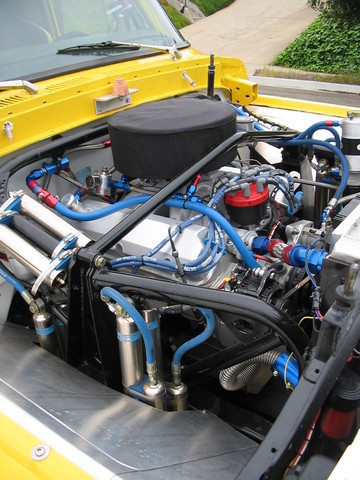 1984 Ford Bronco - A close-up view of a modified engine bay, custom plumbing and an air intake system.