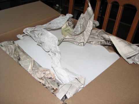 1991 Ford Bronco - A cardboard box contains packing paper and a white object, suggesting a shipment.