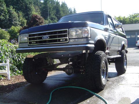 1989 Ford Bronco - This lifted 1989 Ford Bronco features a prominent grille and large off-road tires, suggesting it is ready for terrain.