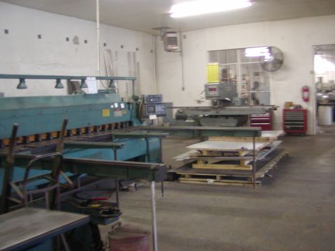 1991 Ford Bronco - This workshop scene features industrial machinery, including a shear and a grinder, with materials ready for processing.
