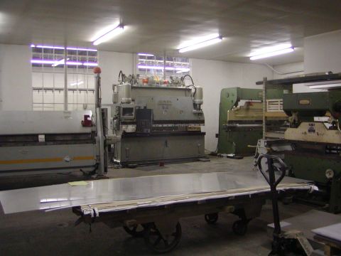 1991 Ford Bronco - A workshop scene heavy machinery used for metal fabrication, with stacks of sheet metal ready for processing.