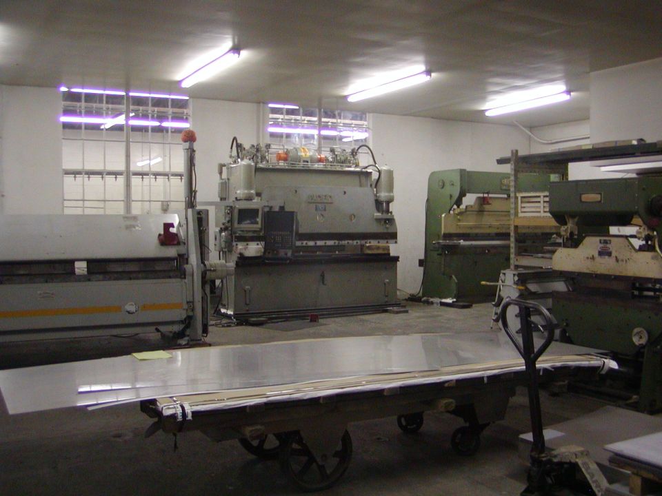 Industrial workshop with large metal fabrication machines and sheet metal on a cart