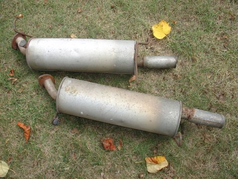 1993 Ford Probe - Two used exhaust mufflers are shown resting on a patch of grass with fallen leaves.