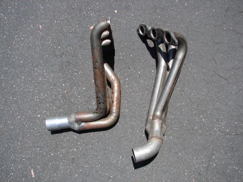 1992 Ford Taurus - Comparison of two exhaust headers, one showing signs of rust and wear, the other appearing new.