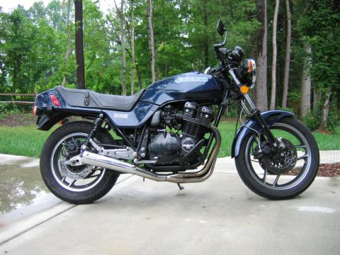 1985 Ford LTD Crown Victoria - Dark blue Suzuki GS1100E standard/naked motorcycle photographed from the right side on a concrete driveway with green woods behind. Feature…