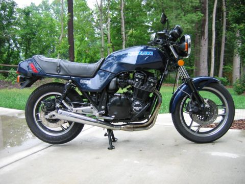 1985 Ford LTD Crown Victoria - Side view of a blue Suzuki GS1100E motorcycle with chrome exhaust and black seat.