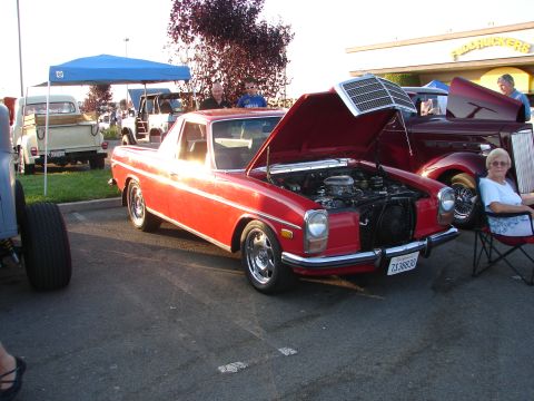 1992 Ford Taurus - A red coupe utility is parked with its hood open, revealing the engine, alongside other vehicles.