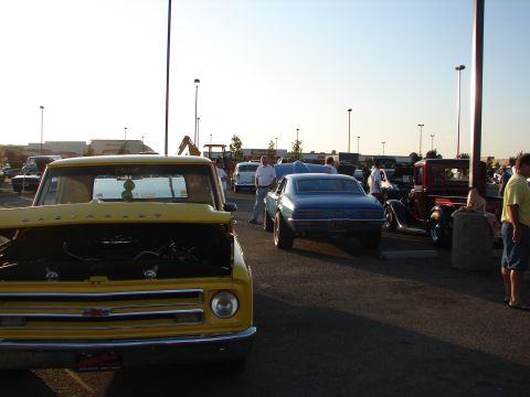 1992 Ford Taurus - A yellow 1967 Chevrolet C10 pickup truck is parked with its hood open at an outdoor car show.
