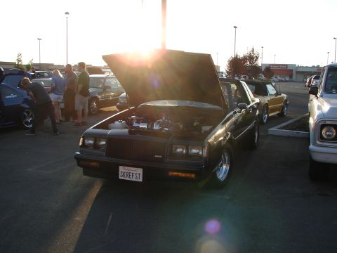 1992 Ford Taurus - A black Buick Grand National is parked with its hood up, revealing the engine bay.