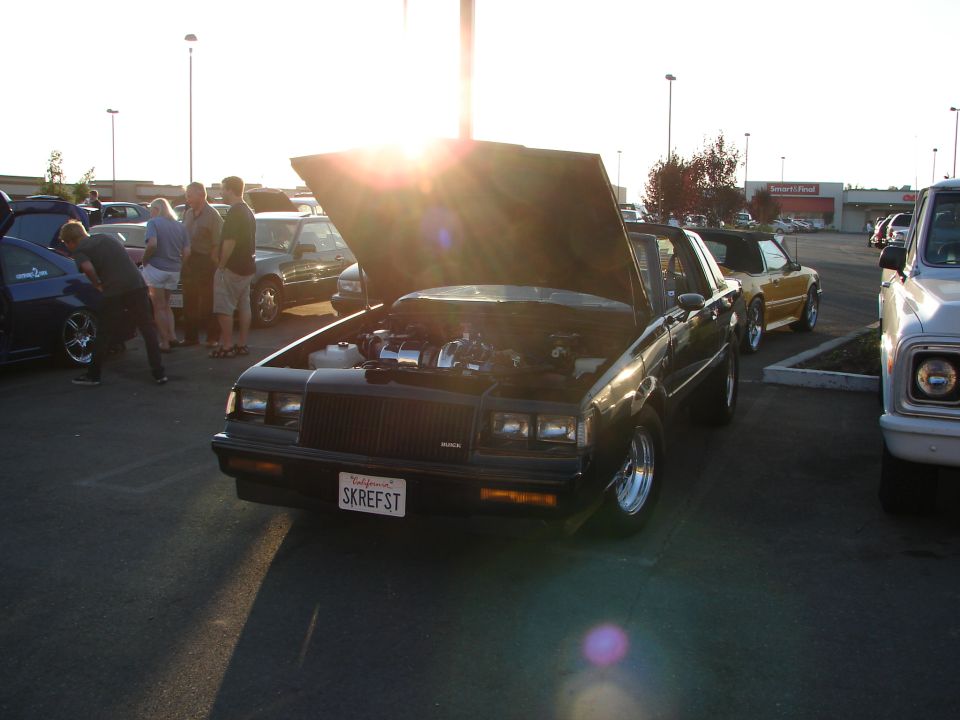 Black Buick Grand National with hood open, showing engine. License plate reads SKREFST