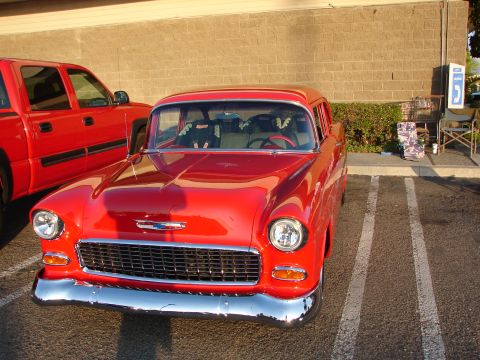 1992 Ford Taurus - A classic red Chevrolet sedan is parked in a lot, with a red pickup truck beside it.