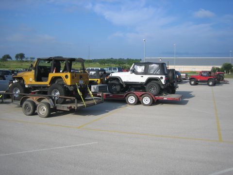 2001 Jeep Wrangler - Multiple Jeep Wranglers are being transported on trailers in a parking lot.