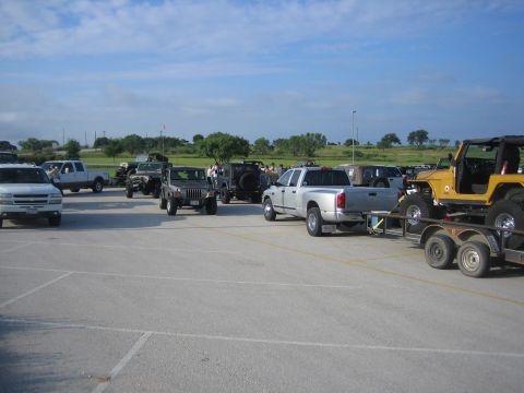 2001 Jeep Wrangler - A collection of Jeeps and trucks are gathered in an outdoor paved area under a partly cloudy sky.