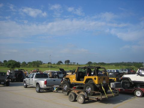 2001 Jeep Wrangler - Multiple Jeep Wranglers and other vehicles gathered outdoors under a partly cloudy sky.