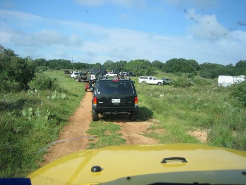 2001 Jeep Wrangler - Multiple Jeeps and SUVs are lined up on a dirt road, heading into a wooded area.
