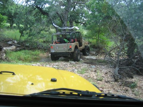 2001 Jeep Wrangler - Two Jeeps navigating a wooded, rocky trail. The tan Jeep Wrangler is in the background.