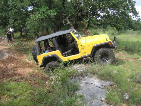 2001 Jeep Wrangler - Yellow 2001 Jeep Wrangler TJ navigating an off-road trail with trees and grass.