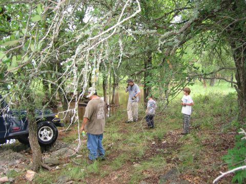 2001 Jeep Wrangler - A group of people observe a Jeep Wrangler navigating a challenging off-road path by a stream.