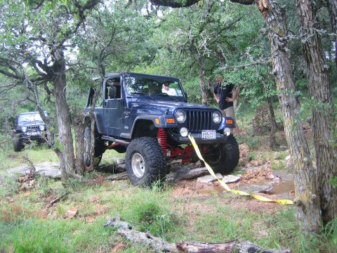2001 Jeep Wrangler - Two Jeeps navigate a rocky, wooded trail with one vehicle winching itself forward.