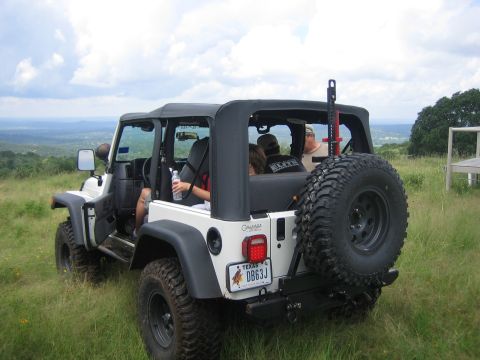 2001 Jeep Wrangler - A white Jeep Wrangler is parked on a grassy overlook with people inside, enjoying the view.