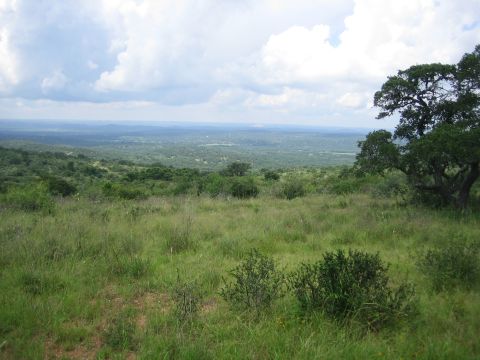 2001 Jeep Wrangler - A wide view of a valley with rolling hills and scattered trees, under a partly cloudy sky.