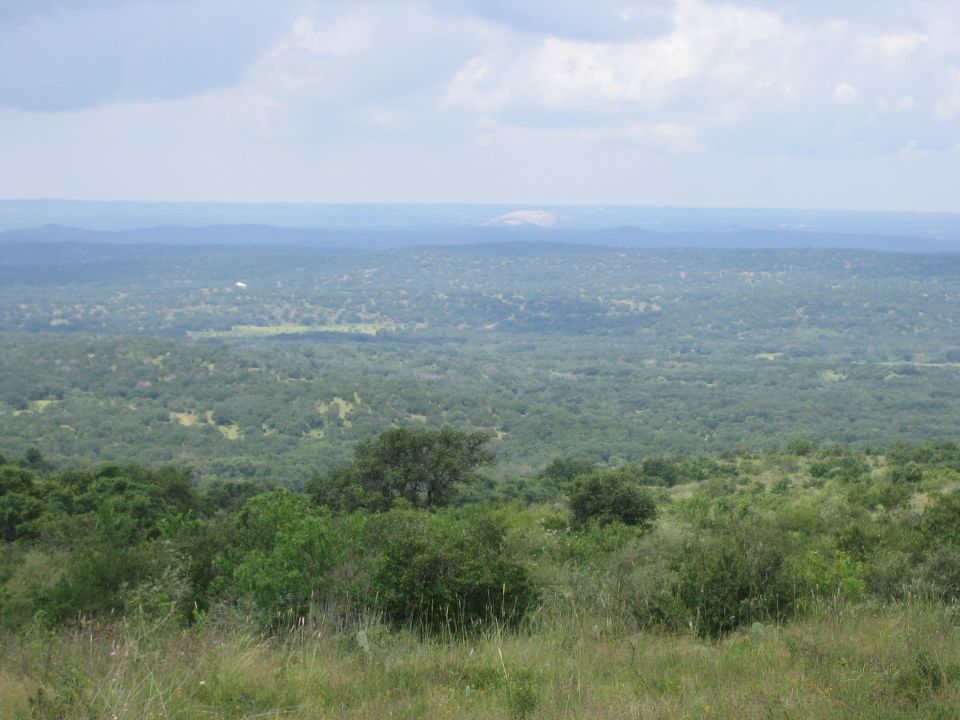 Wide landscape view of rolling hills covered in dense green trees and brush