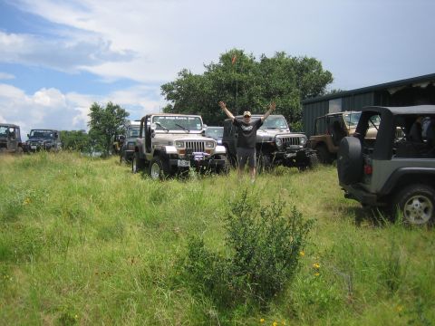 2001 Jeep Wrangler - A group of Jeep Wranglers are gathered in a grassy area on a cloudy day.