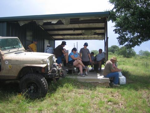 2001 Jeep Wrangler - A group of people relax under a covered shelter next to a parked Jeep Wrangler.