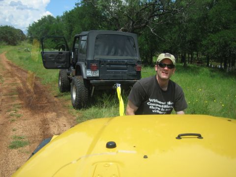 2001 Jeep Wrangler - A yellow vehicle is in the foreground, with a black 2001 Jeep Wrangler being towed behind it on a dirt road.
