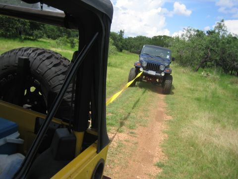 2001 Jeep Wrangler - Two Jeep Wranglers on a dirt path, one towing the other with a yellow strap.