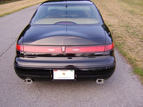 1996 Mercury Grand Marquis - The rear of a black Lincoln Mark VIII is shown, its distinctive taillight bar and dual exhaust pipes.