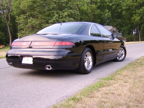 1996 Mercury Grand Marquis - This black coupe, likely a 1995 model, is viewed from the rear with chrome wheels and dual exhaust pipes visible.