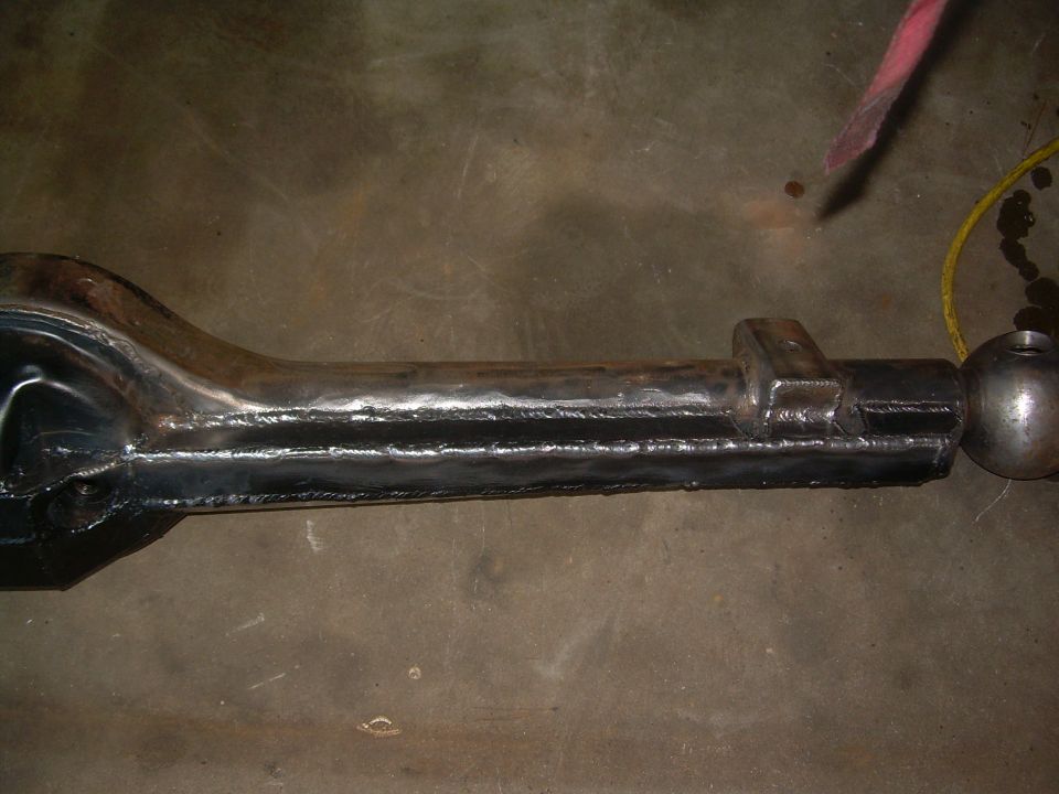 Differential housing with visible welds and a spherical end, resting on a concrete floor