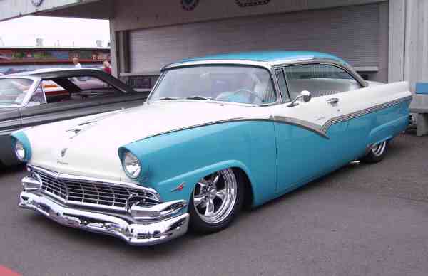 White and turquoise coupe with chrome grille and custom wheels, parked outdoors