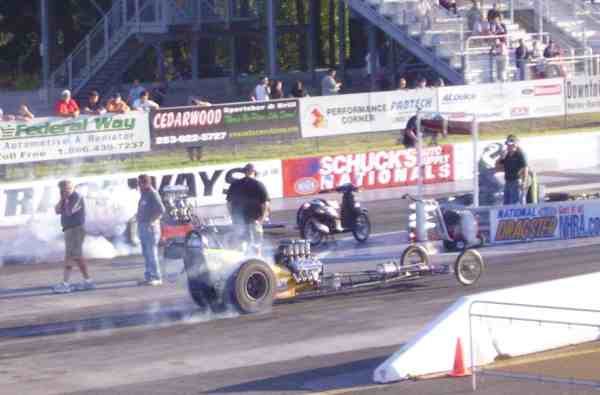 Dragster with smoking tires on a race track, people watching from stands
