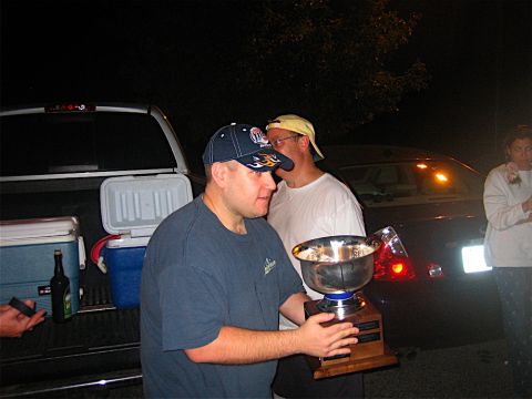 1985 Ford LTD Crown Victoria - People gather around a trophy next to a truck and a sedan at night.