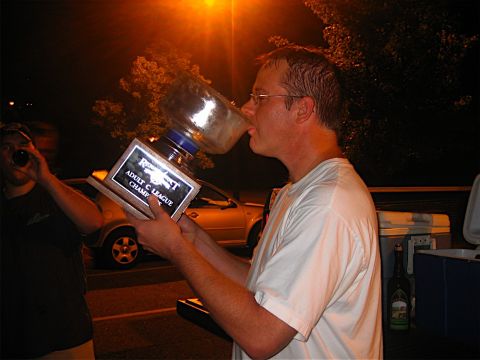 1985 Ford LTD Crown Victoria - A man drinks from a trophy while a silver sedan is parked behind him.