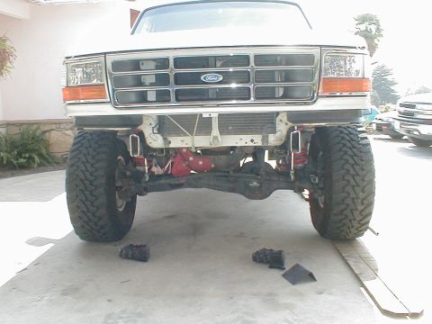 1996 Ford Bronco - Front view of a white Ford Bronco with its bumper removed, revealing the suspension and engine components.