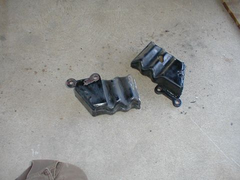 1996 Ford Bronco - Two damaged black metal components are lying on a concrete floor.