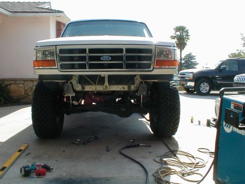 1996 Ford Bronco - The front of a lifted Ford truck is shown, with a black SUV visible in the background.