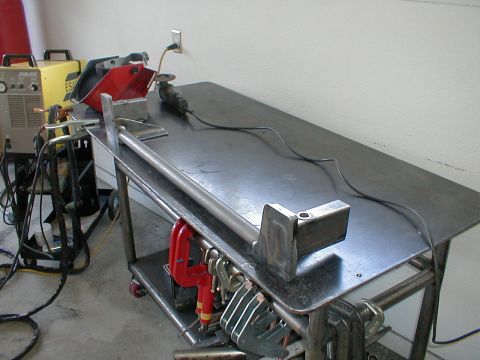 1996 Ford Bronco - A metal fabrication setup includes a welder, grinder, and metal pieces on a workbench, ready for work.