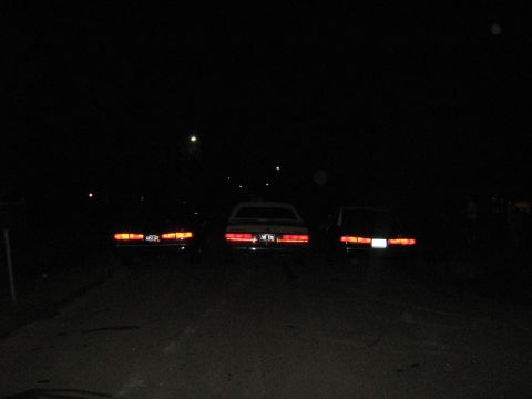 1988 Mercury Grand Marquis - Three cars are parked in a dark area at night, their taillights illuminated.